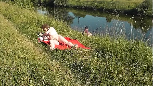 XXX MILF sexy Frina on river bank undressed and sunbathes naked. Random man fisherman watching for her, and in the end decided to join naked woman. Wild beach. Nudist beach. Public nudity. Public exposure. Naked in public fresh Movies